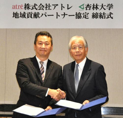 協定書を交わし握手をする株式会社アトレ井上浩司取締役（左）と跡見裕学長