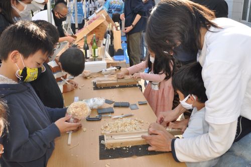 塩尻市ブースで割り箸作りを指導する学生